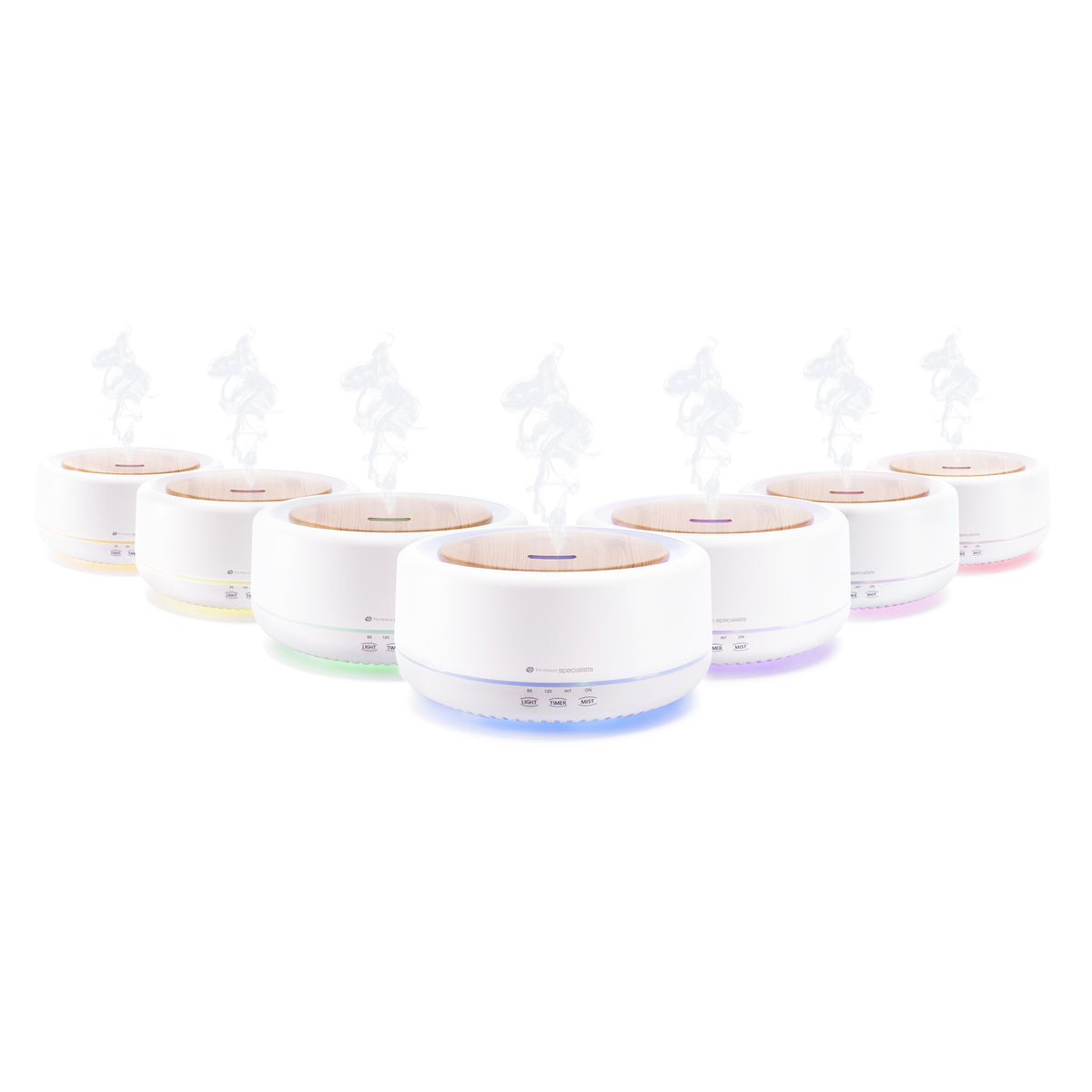 A row of seven Rio ENYA Aroma Diffuser, Humidifier & Night Light units, each with a round white body and wood top, emits mist and features LED bases glowing in green, blue, purple, and pink to create a soothing atmosphere.