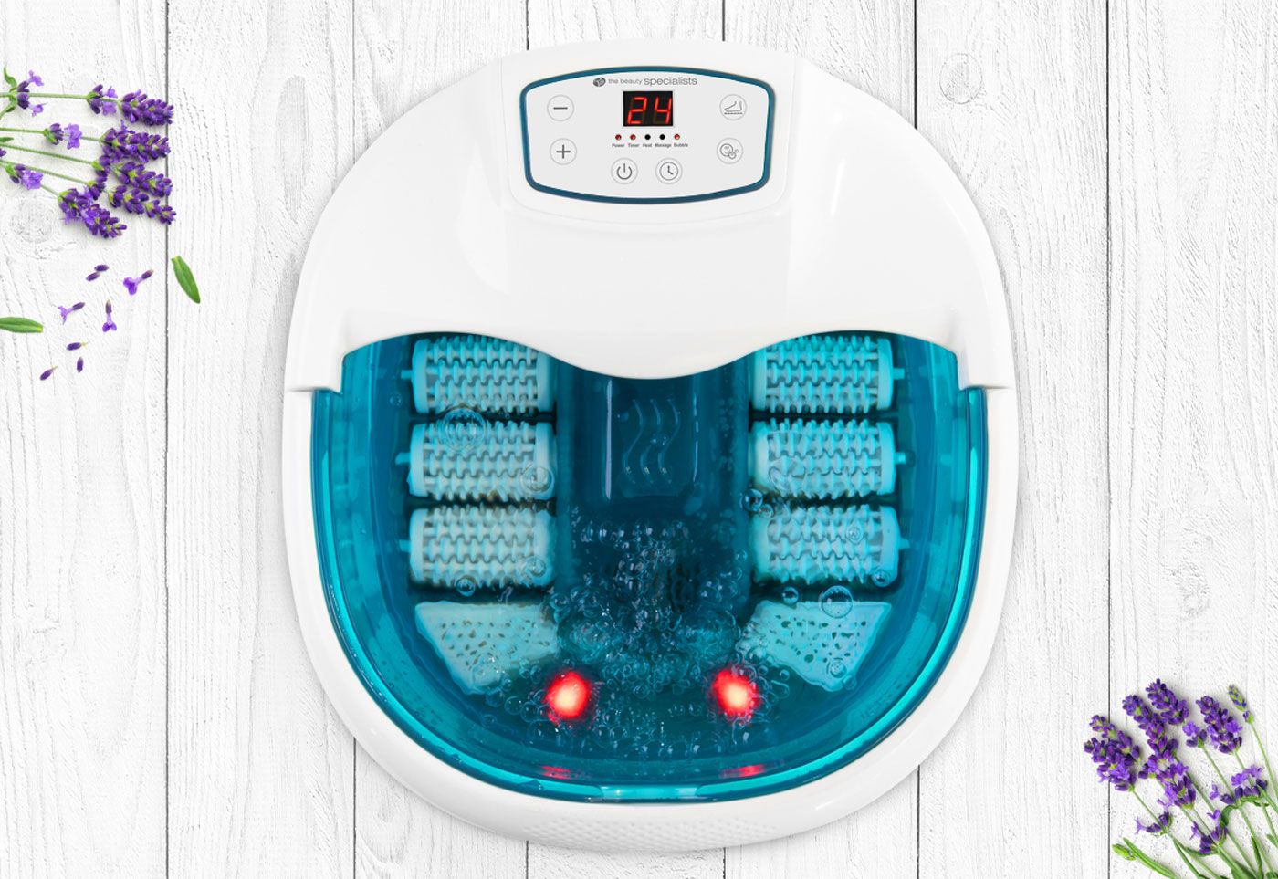 motorised roller foot spa bath filled with bubbling water placed on light wash wooden floor surrounded by lavender