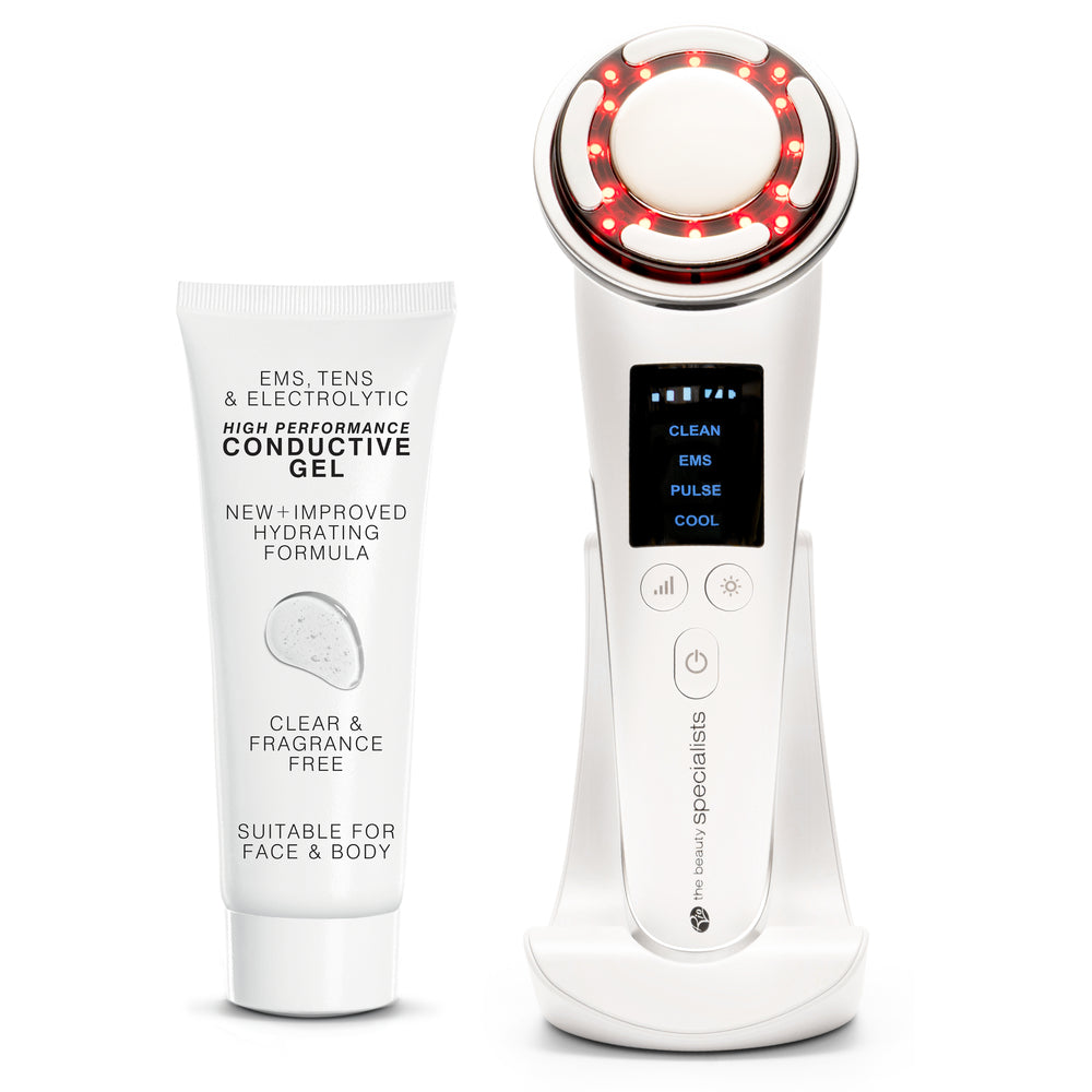 A white tube of conductive gel is placed beside the Rio Face Lift &amp; Tone Beauty Spa device, featuring a digital screen, control buttons, red LED lights, and a charging stand—both designed for skincare treatments and firmer-looking skin.