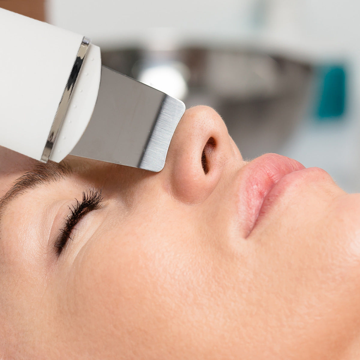 A close-up shows a person with eyes closed, enjoying relaxation as the Rio Ultrasonic Skin Cleanser is applied to their nose for deep cleansing and exfoliation. The background is softly blurred, highlighting the skincare routine.