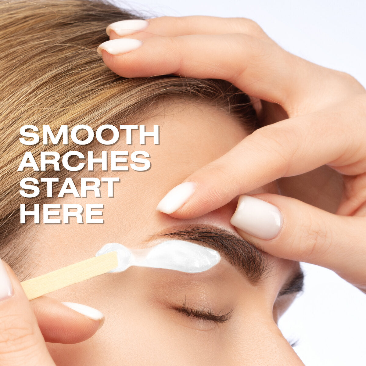 A close-up of a womans closed eye as Rio Coconut Go Smooth Stripless Hard Wax Beads (100g) are applied to her eyebrow with a wooden spatula. Text reads, SMOOTH ARCHES START HERE. Well-groomed hands promise smooth skin results.