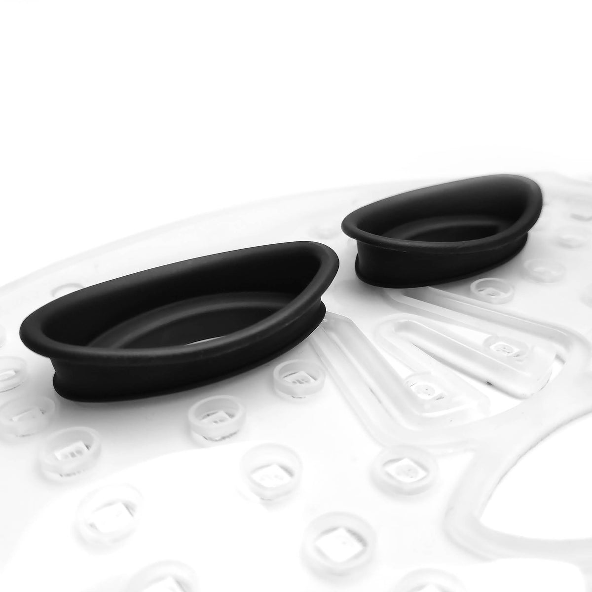 Close-up of two black, oval silicone inserts on a white surface—accessories for the Rio faceLITE beauty boosting LED face mask, designed to energize and rejuvenate ageing skin.
