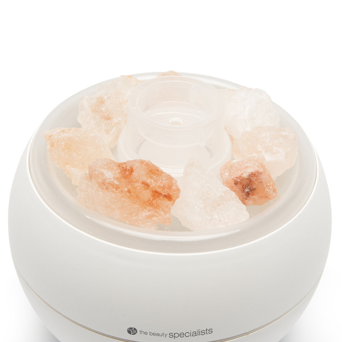 The Rio Aroma Diffuser, Humidifier & Night-Light with Himalayan Rock Salt is a white, round unit featuring large Himalayan salt pieces around its top and is labeled the beauty specialists at the base.
