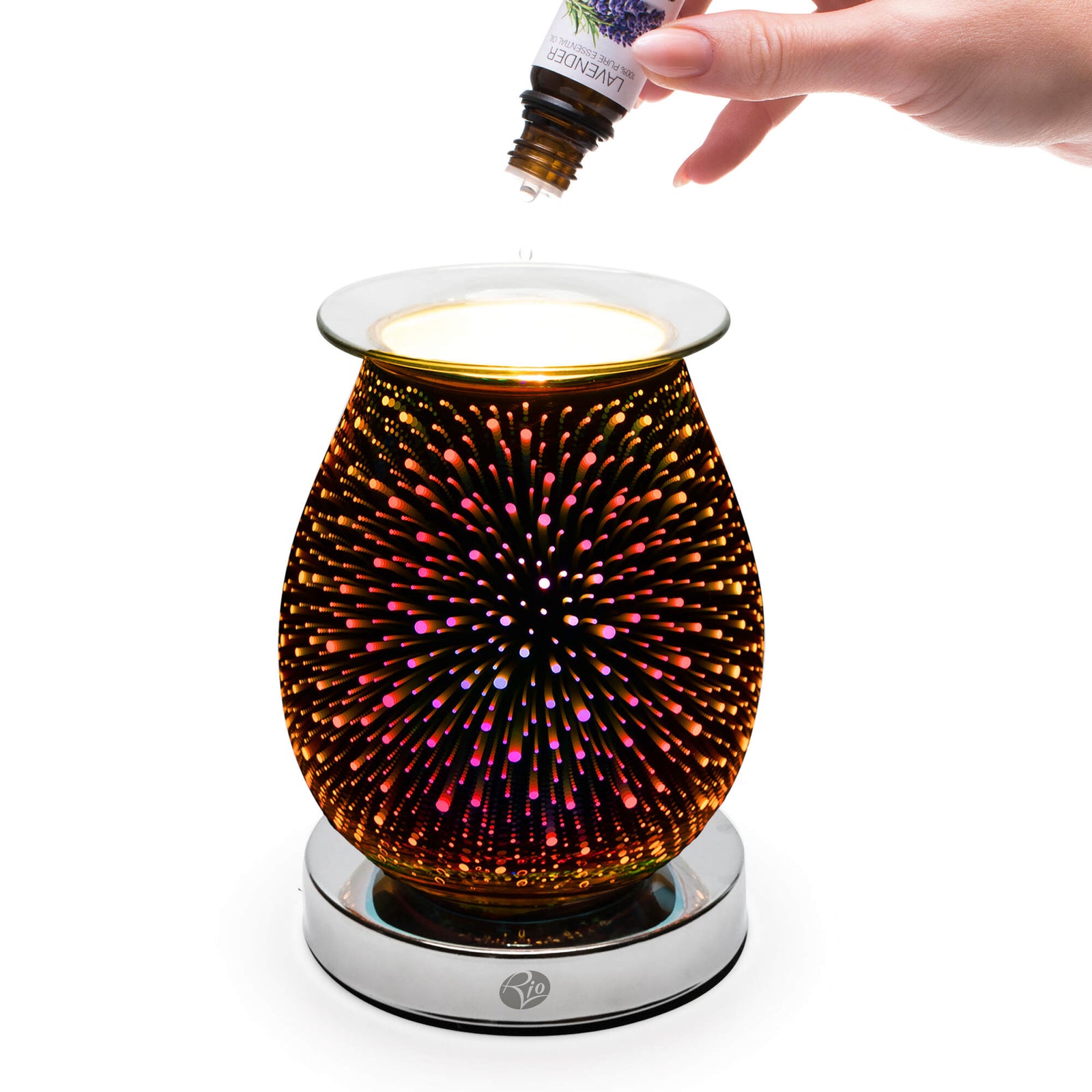A hand drips lavender oil into the Rio Alura Wax Melt Burner & Aroma Diffuser Lamp, featuring a vibrant starburst design and metallic base—perfect for stylishly diffusing fragrance or melting wax.