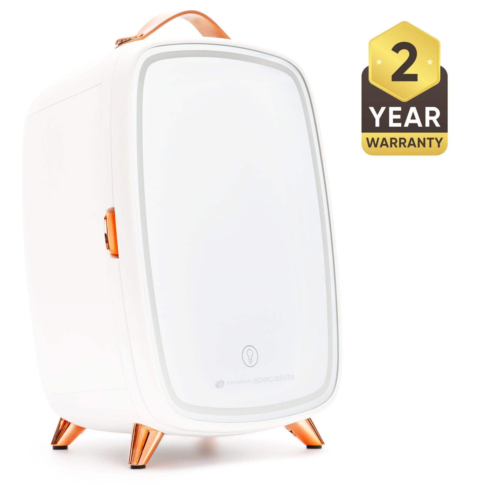 The Rio Beauty Skincare Fridge With Mirror is a sleek white mini fridge with copper accents, a leather handle, and four angled legs, ideal for chilling creams. A black and gold badge displays "2 Year Warranty" on the right side.