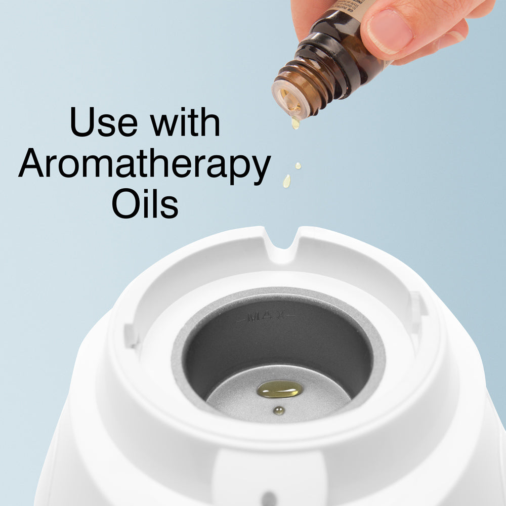 A hand pours aromatherapy oil into the reservoir of the white Rio Facial Sauna Skincare Spa with Steam Inhaler. Text on image: Use with aromatherapy oils for your home spa facial treatment.
