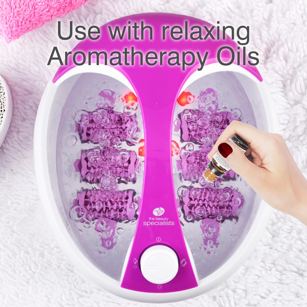 A hand adds aromatherapy oil to a Rio Deluxe Foot Spa Bath and Massager - Purple filled with bubbling water. Bold text above reads, Use with relaxing Aromatherapy Oils.