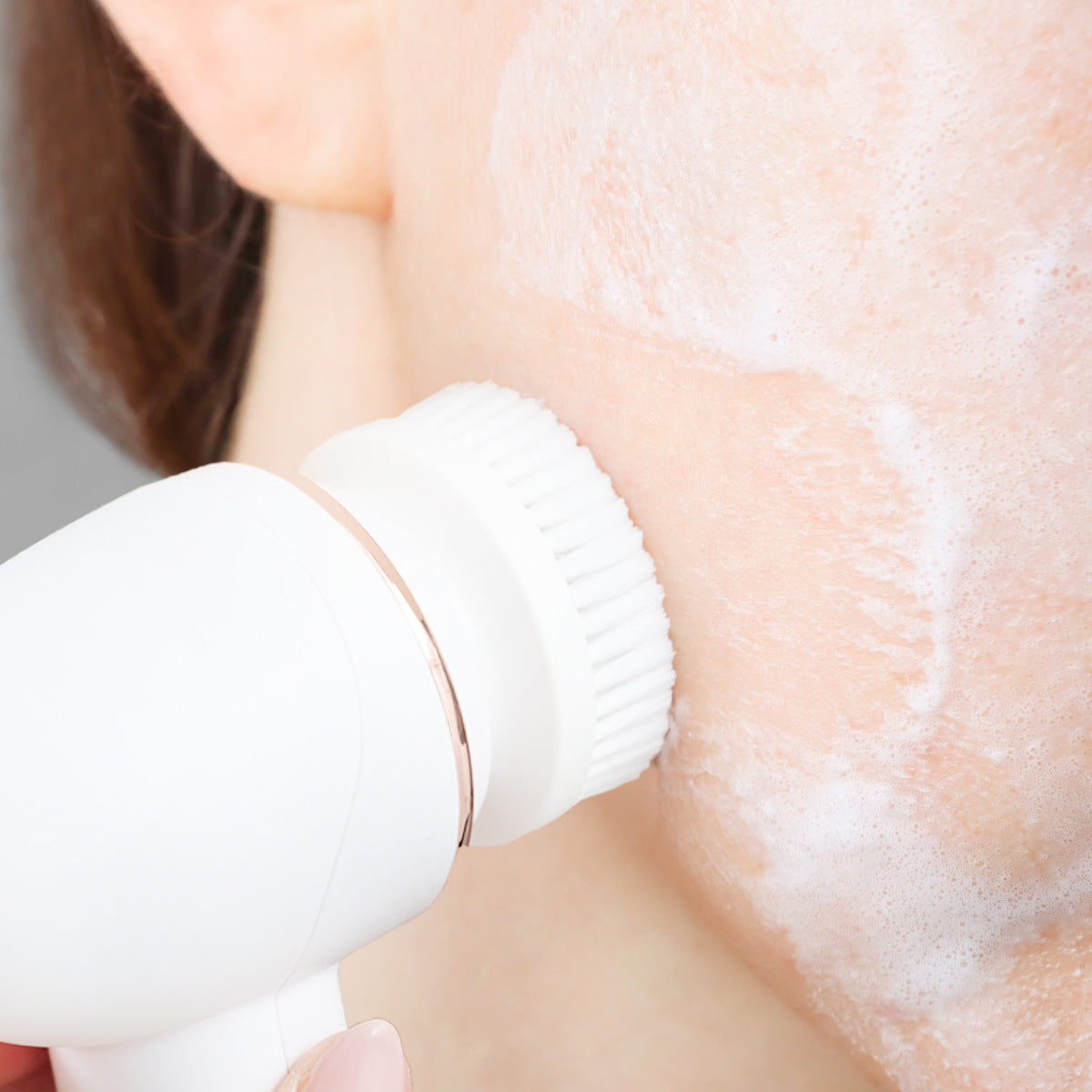 A close-up of a person’s cheek being deep cleansed with the PURE CLEANSE Deep Cleansing & Exfoliating Facial Brush by Rio the Beauty Specialists, creating a rich lather on their skin.