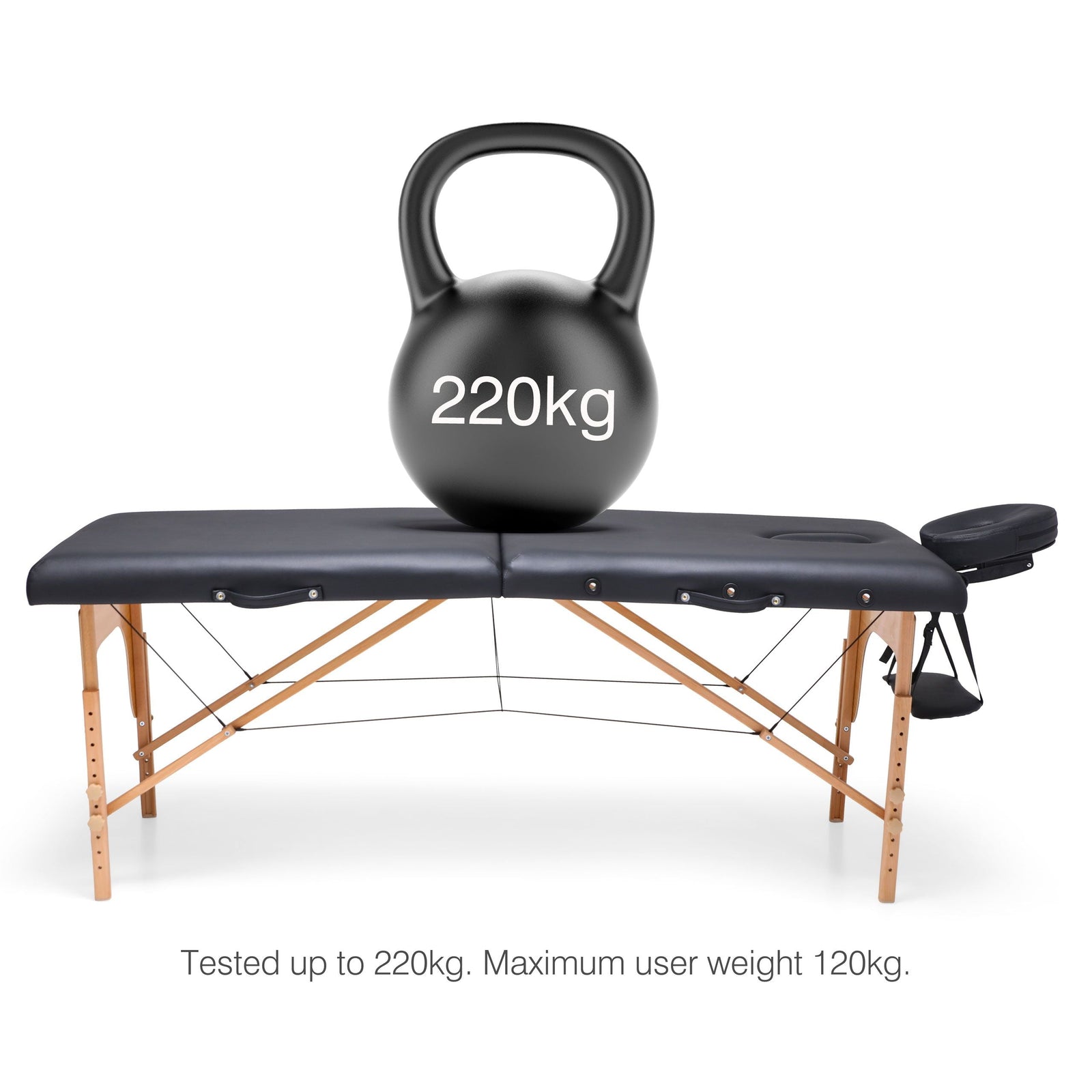 A Rio Professional Ultra-Light Portable Massage Table with wooden legs supports a 220kg kettlebell. Text reads: Tested up to 220kg. Maximum user weight 120kg—designed for professional massage treatments.
